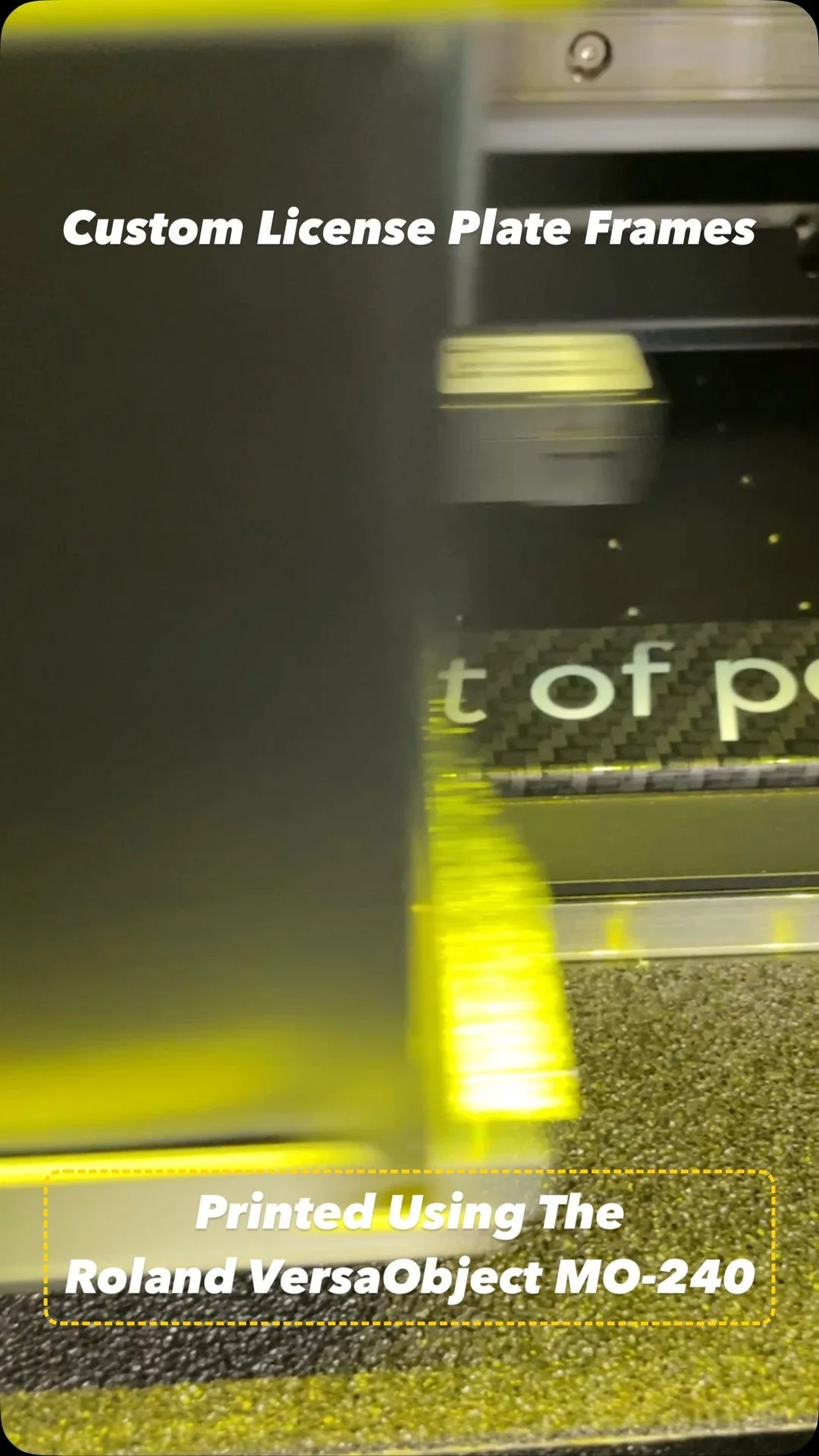 Roland VersaObject MO-240 UV printer mid-pass on a custom carbon-fiber license plate frame, neon UV-cure light bar visible — Print the Chicken Orange County studio